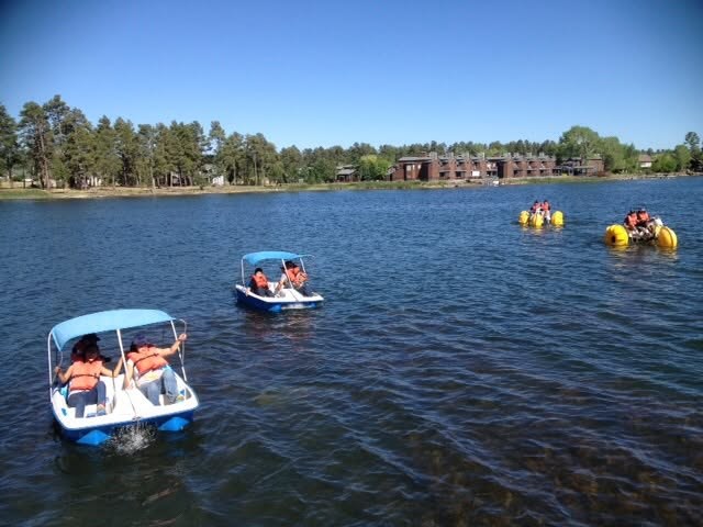 Guests enjoying paddle boats on Rainbow Lake, with the tree-lined shore beyond