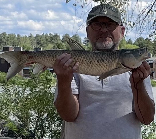 An angler holding a large catch beside Rainbow Lake